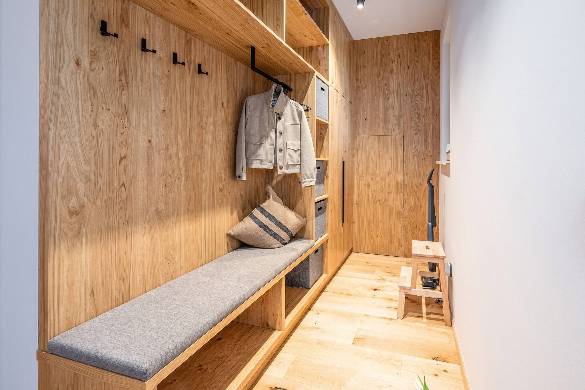 Une pièce en bois avec un banc, une petite table et un portant sur lequel sont suspendus des vêtements.