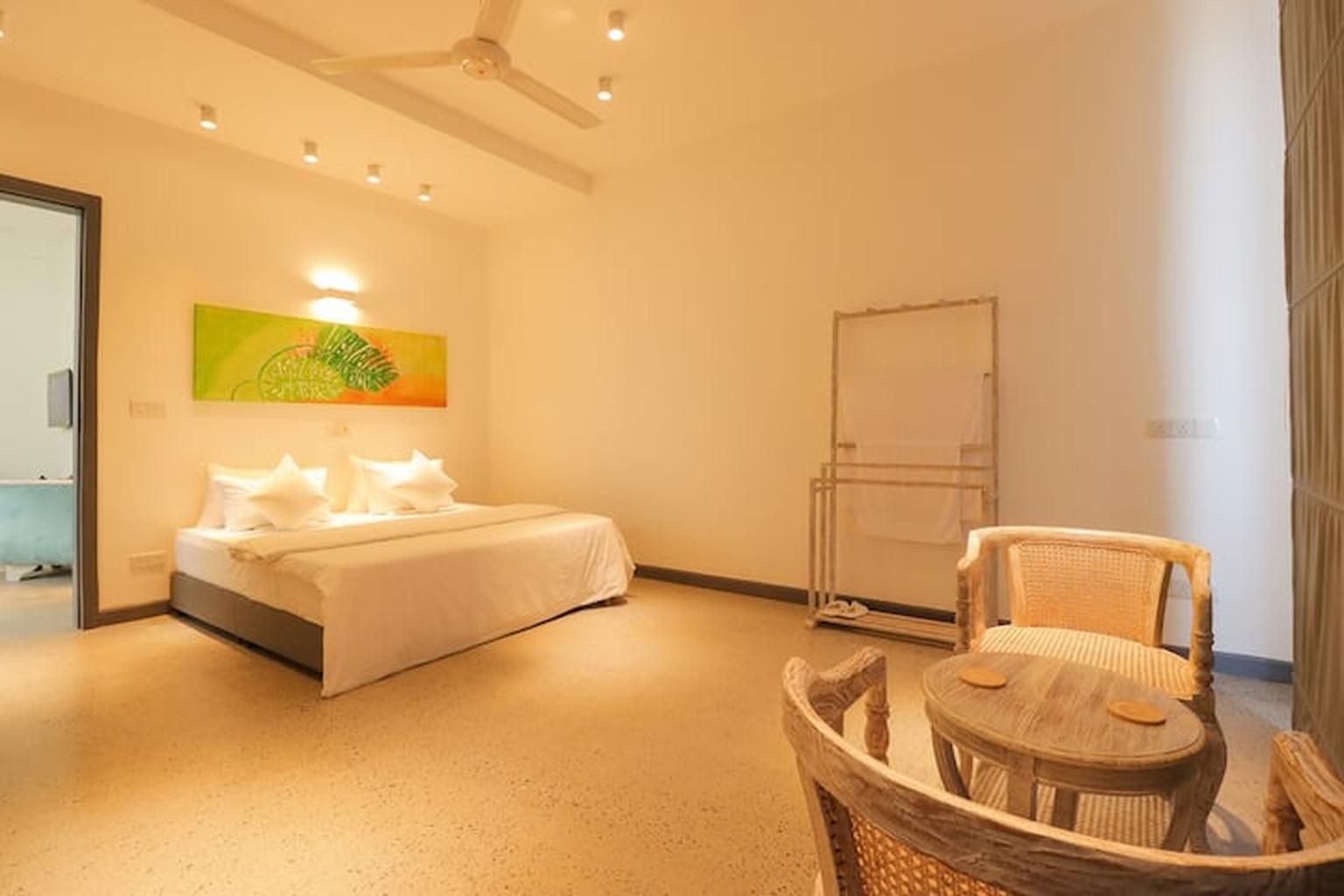 Una habitación de hotel con una cama, una silla, una mesa, un cuadro en la pared y una pizarra.