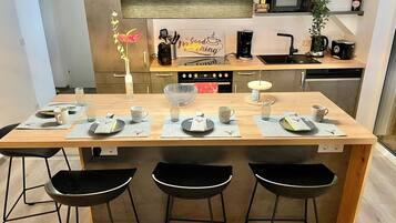 A modern kitchen with a central island, bar stools, and a coffee station.