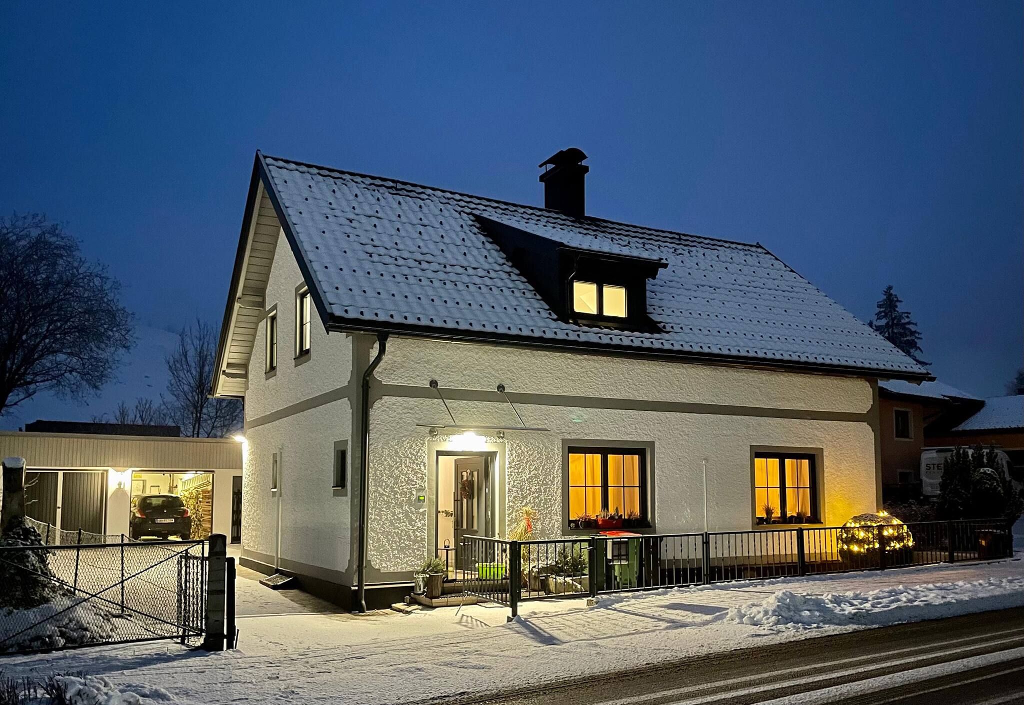 Ein zweistöckiges Haus mit schneebedecktem Dach und einem sichtbaren Schornstein.