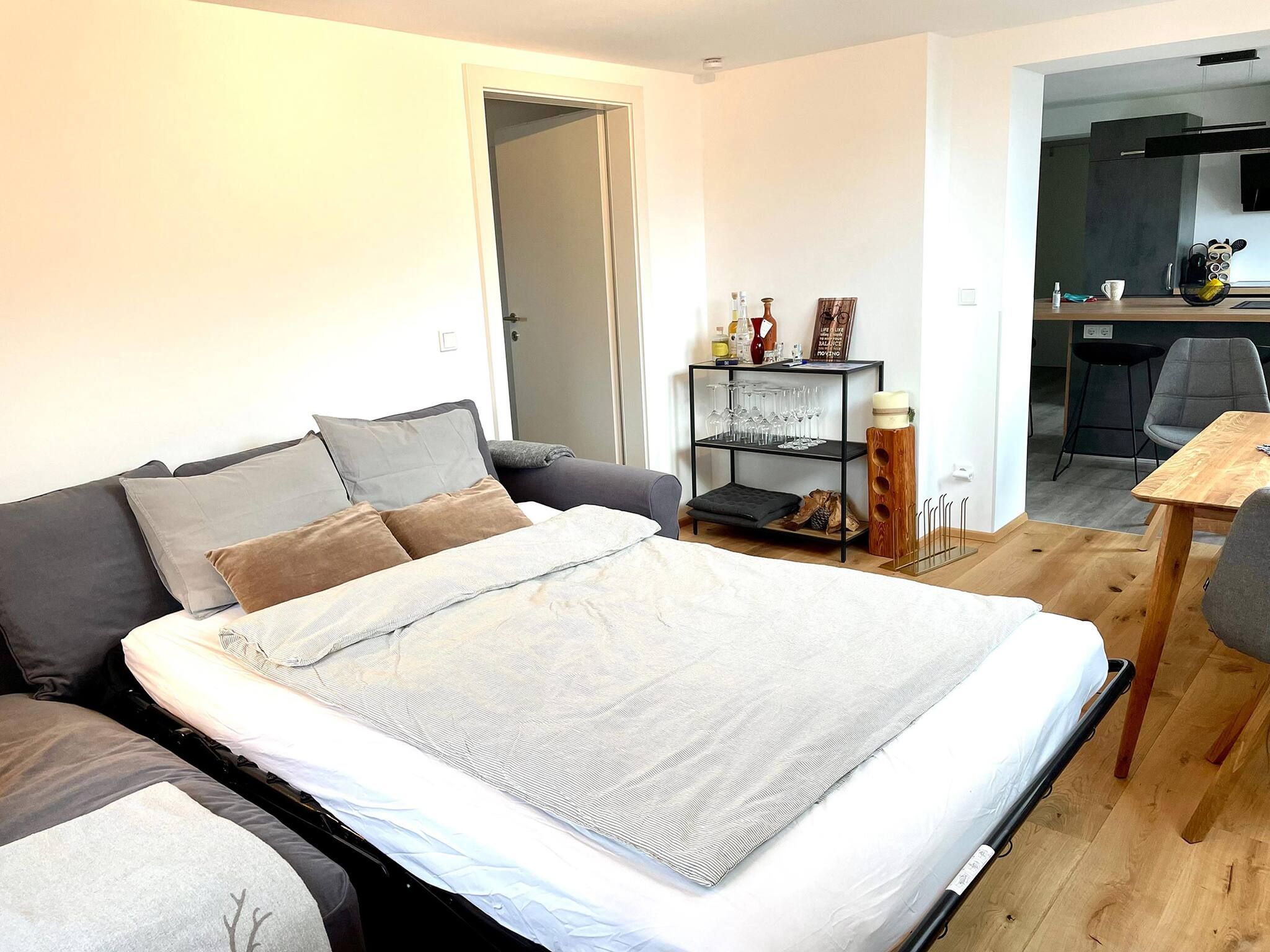 Una camera da letto moderna con un letto grande, un divano, un tavolino e un angolo cottura sullo sfondo.