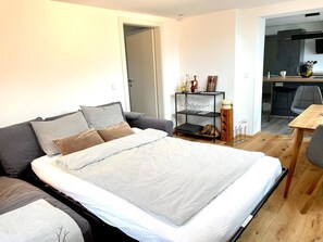 Una camera da letto moderna con un letto grande, un divano, un tavolino e un angolo cottura sullo sfondo.