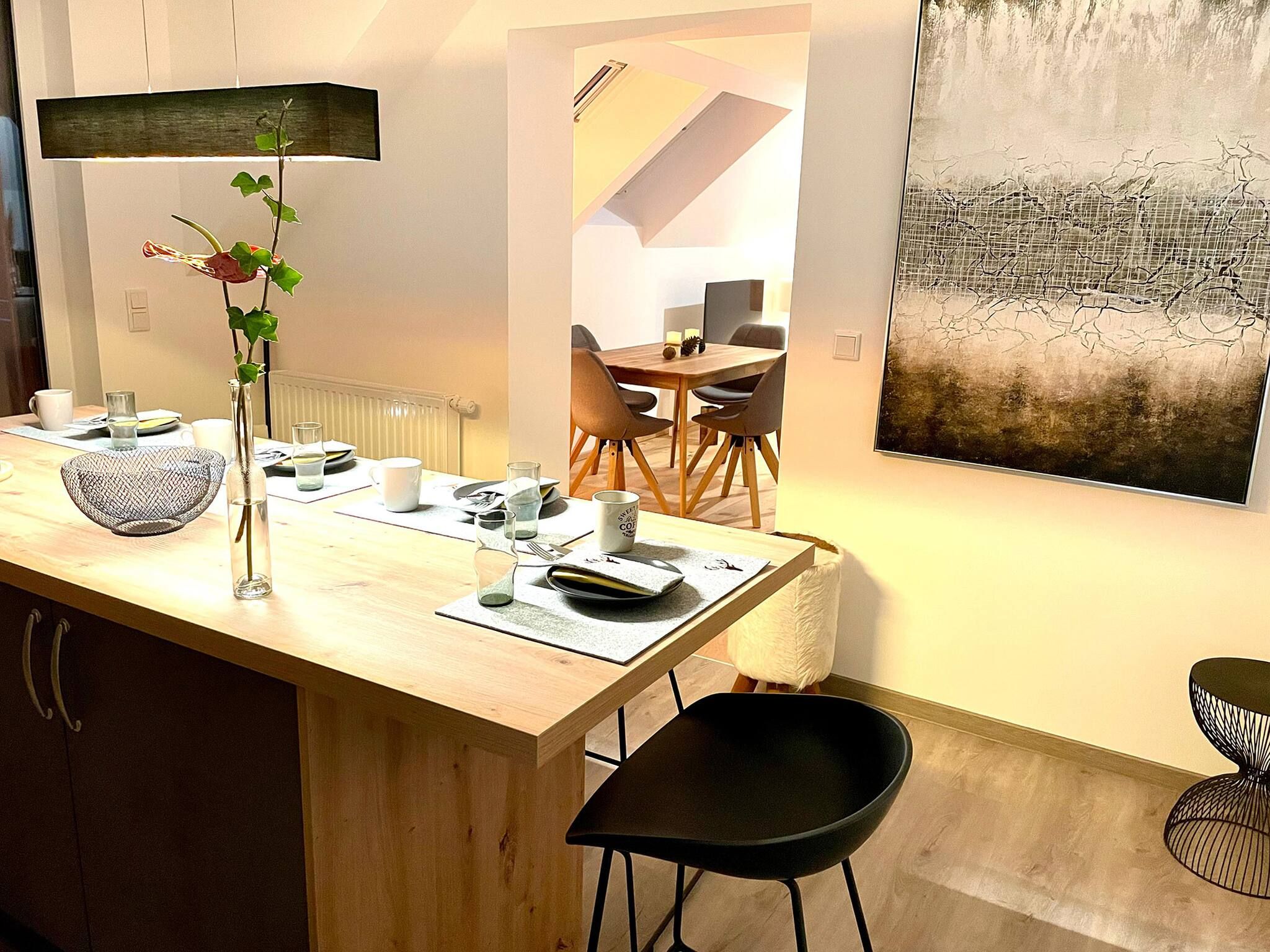 Una cucina moderna con un piano di lavoro in legno, un vaso con fiori e un'area pranzo con sedie e tavolo.