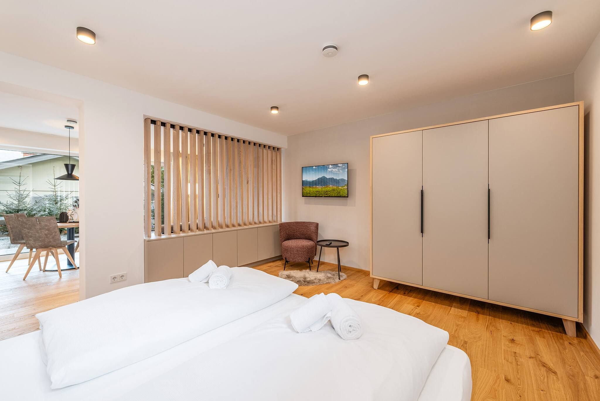 Una habitación de hotel con dos camas, un armario, una silla y una mesita.