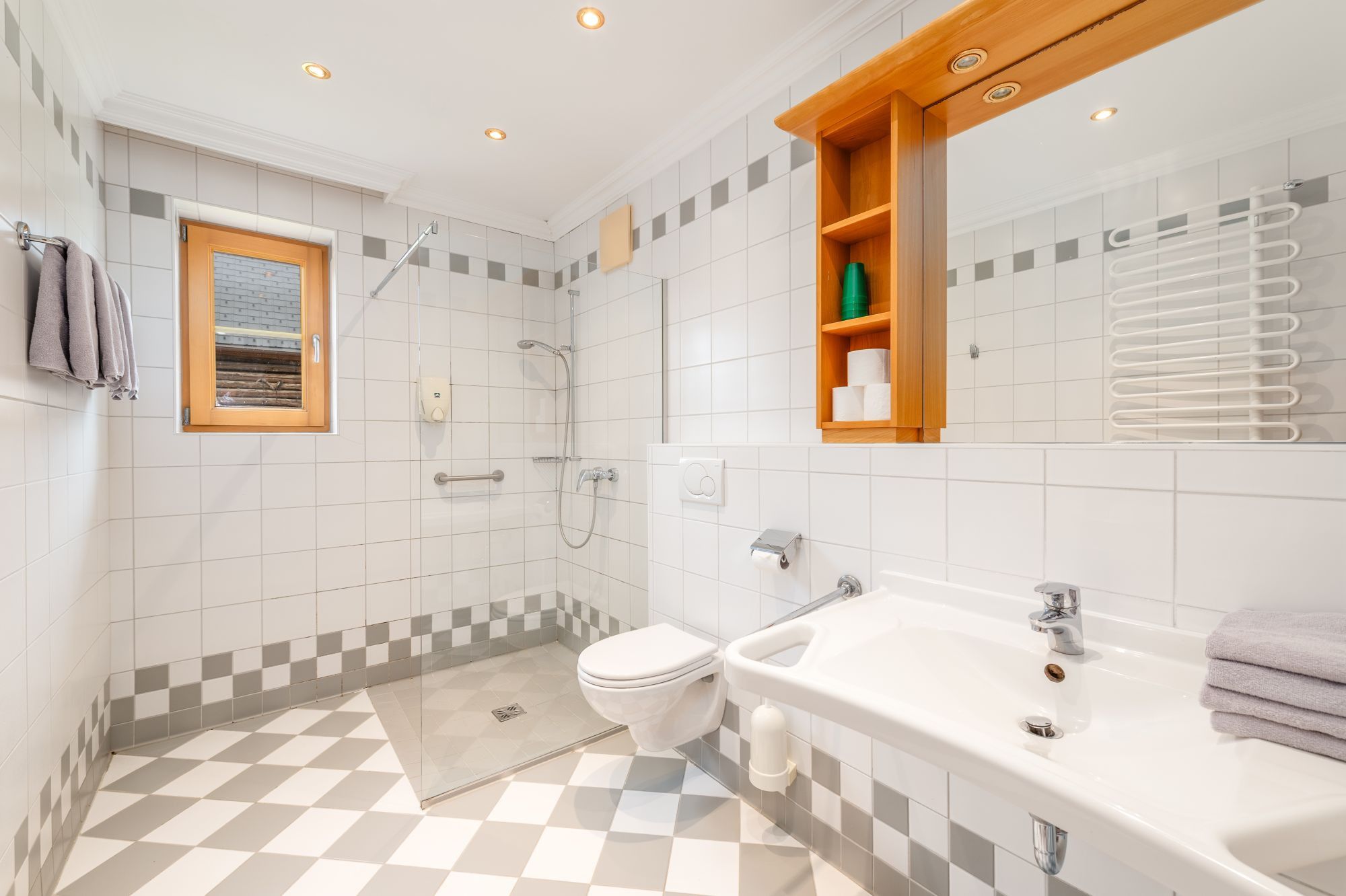 Ein modernes Badezimmer mit Schachbrettboden, Toilette, Waschbecken und Dusche.