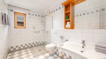 Ein modernes Badezimmer mit Schachbrettboden, Toilette, Waschbecken und Dusche.
