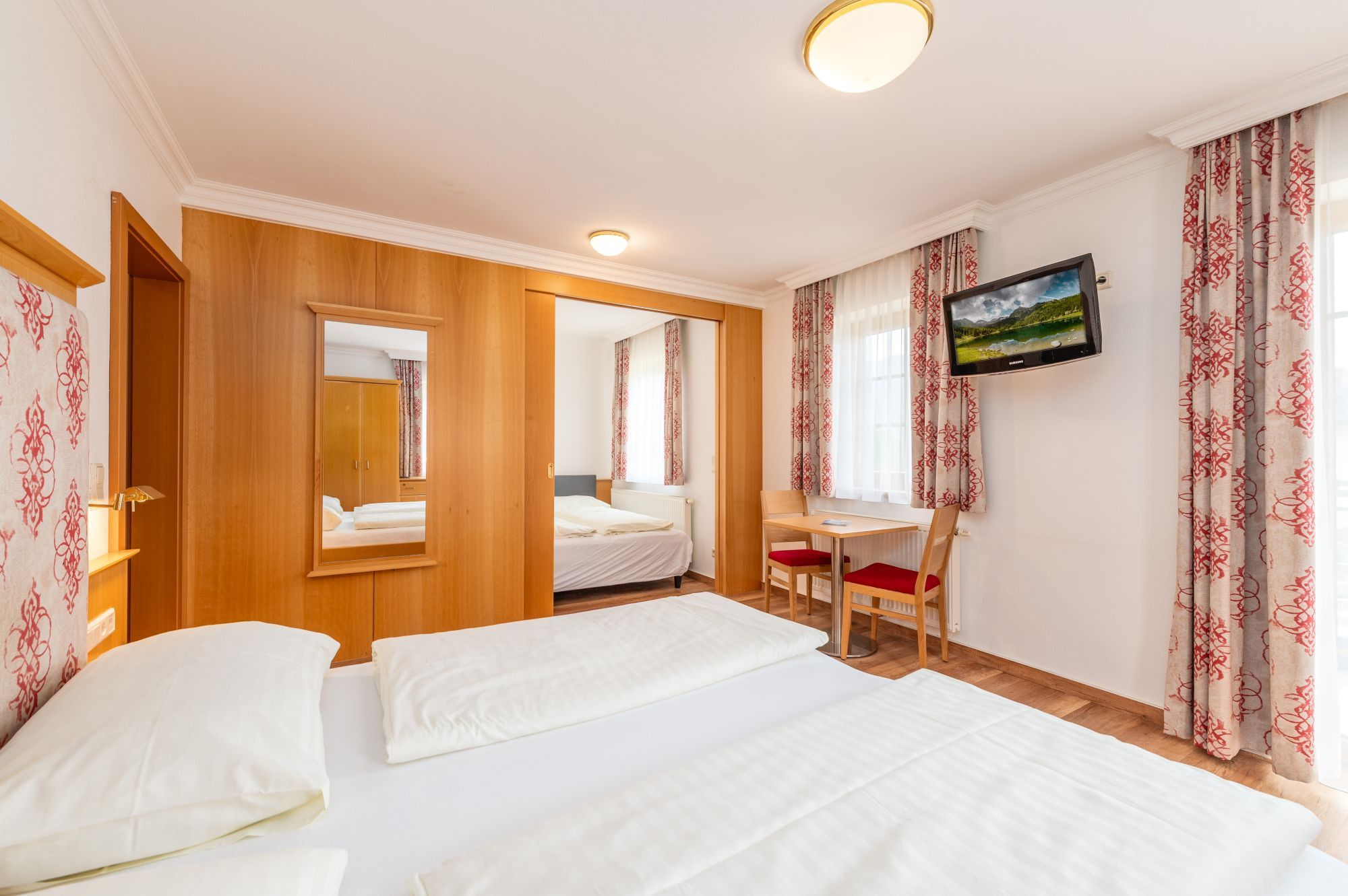 Habitación de hotel con dos camas, un escritorio, una silla, un televisor y un armario.