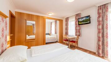 Habitación de hotel con dos camas, un escritorio, una silla, un televisor y un armario.
