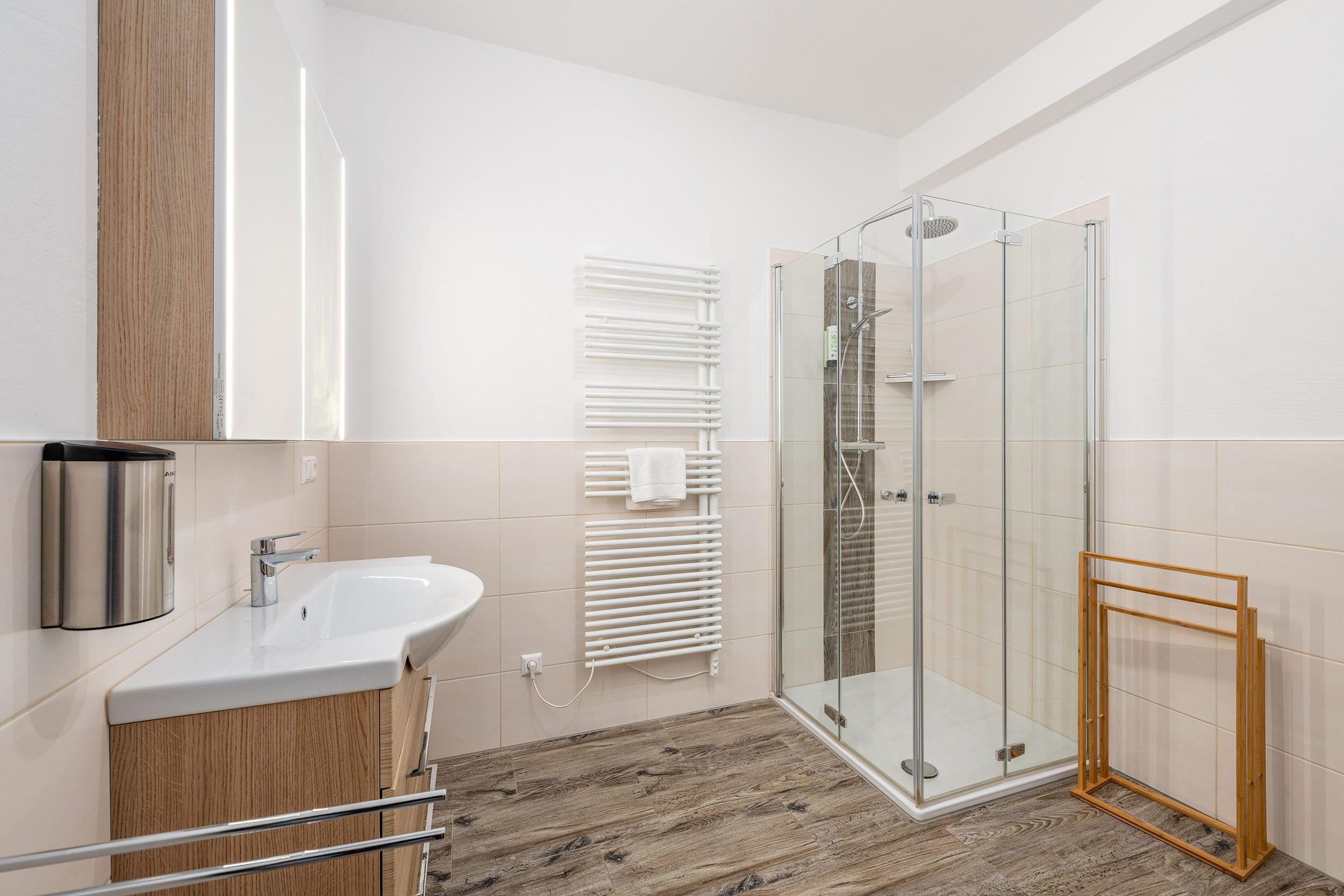 Ein modernes Badezimmer mit Duschkabine aus Glas, integriertem Waschbecken und Holz-Waschtisch.