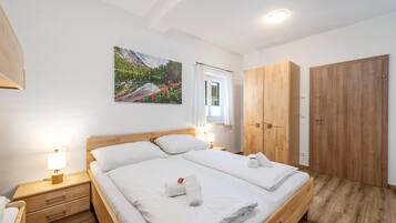 Ein Schlafzimmer mit einem hölzernen Bett, zwei Nachttischen mit Lampen, einem Fenster mit Vorhängen, einem Holzschrank und einem Bild an der Wand.