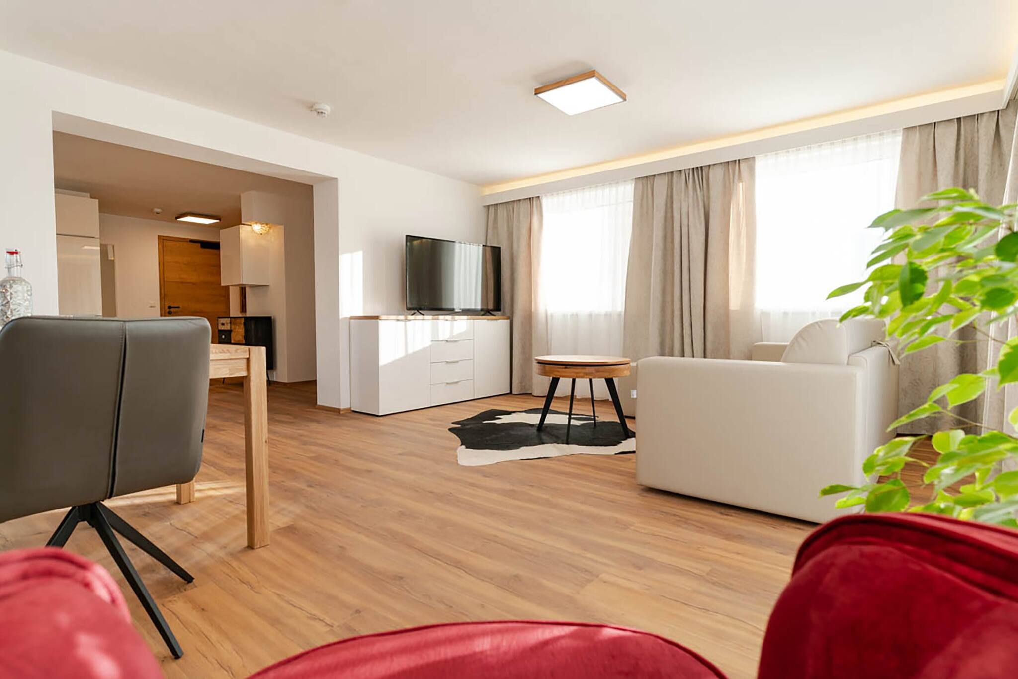 A modern living room with a sofa, a television, and a dining area with a table and chairs.