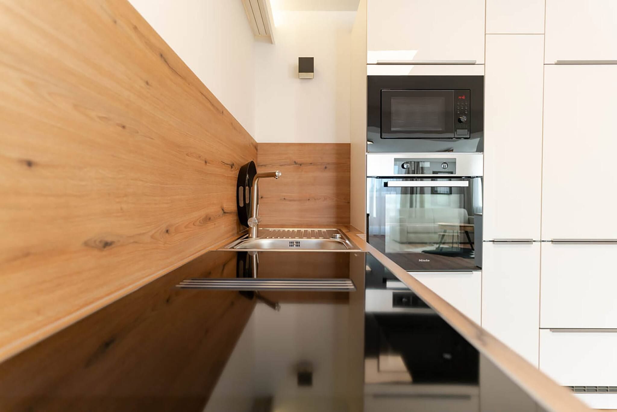 A modern kitchen with a wooden countertop, stainless steel appliances, and white cabinetry.