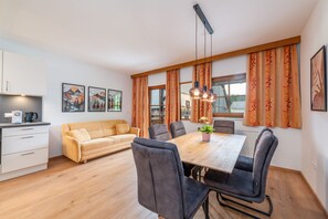 Ein moderner Essbereich mit einem Holztisch, grau gepolsterten Stühlen und einer Couch.