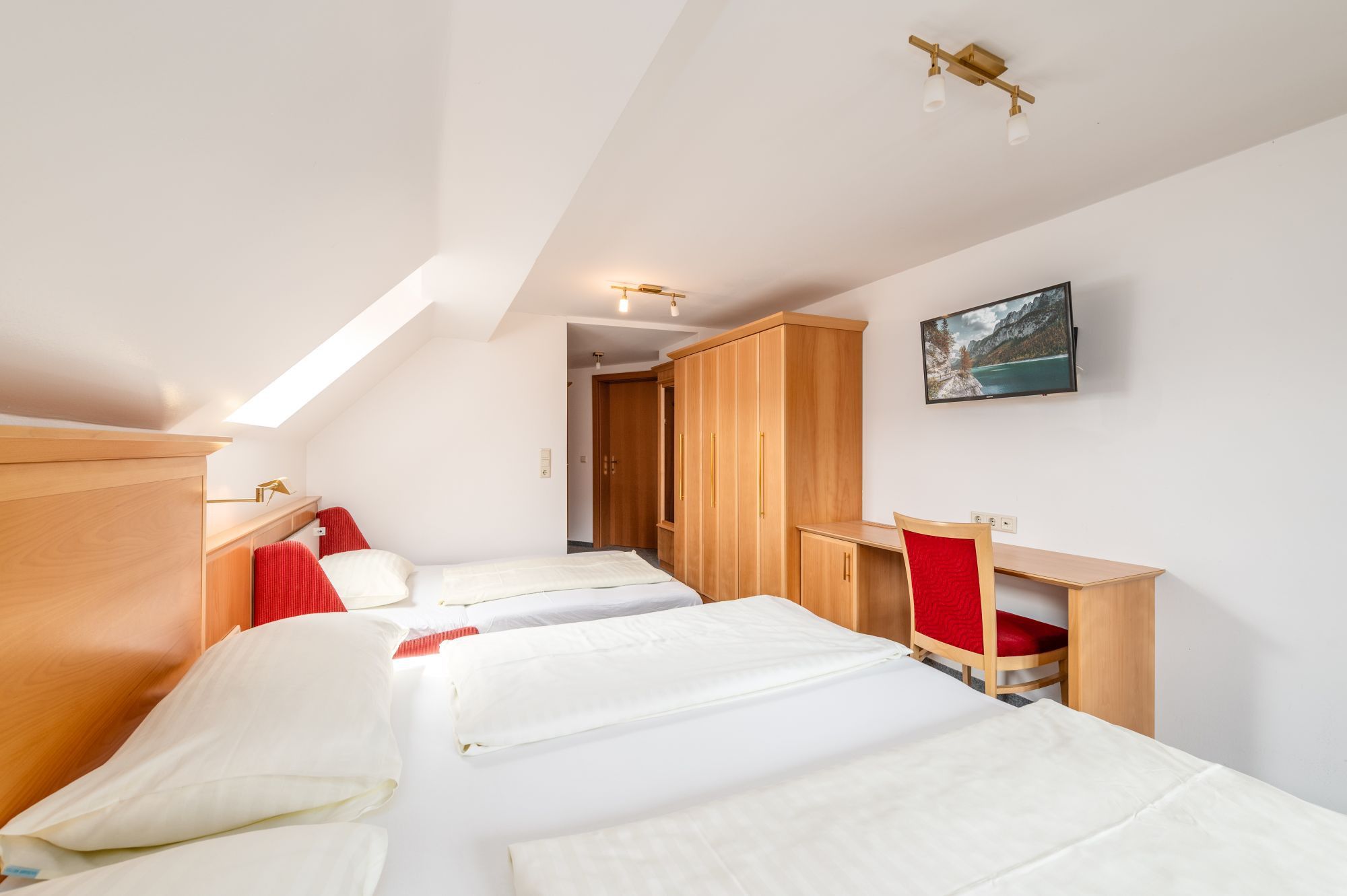 Een slaapkamer met twee bedden, een bureau, een stoel en een kledingkast.