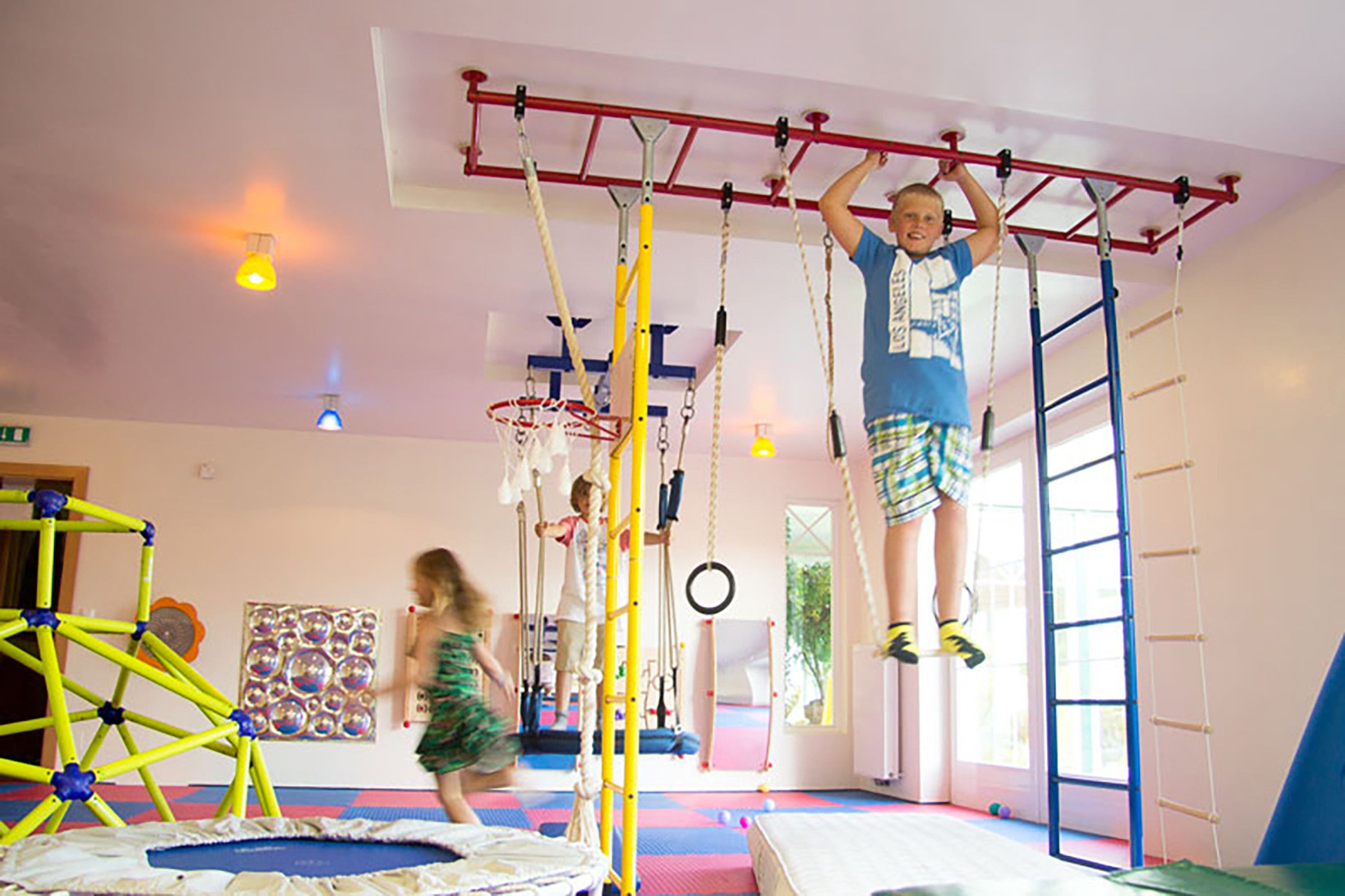 Een sportzaal met klimconstructies en een trampoline.