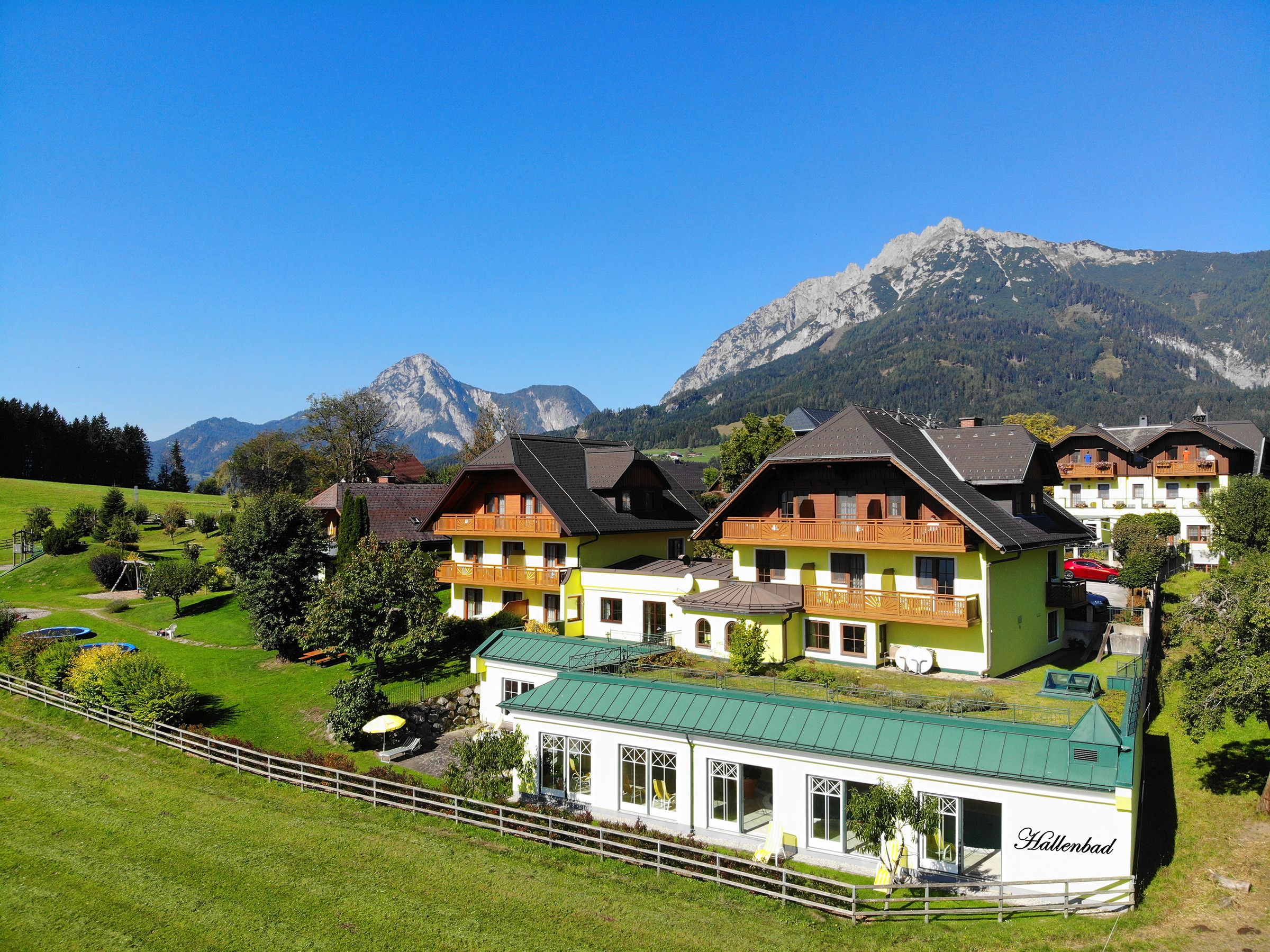 Een hotel in chaletstijl met meerdere balkons, gelegen tegen een achtergrond van bergen en een heldere lucht.