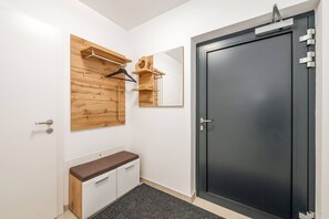 Ein modernes Badezimmer mit einem Holzbadezimmerunterschrank, einem Spiegel, einer schwarzen Tür und einem hängenden Kleiderhaken.