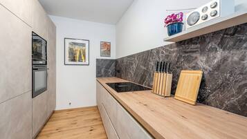 Eine moderne Küche mit einer Holzarbeitsplatte, einem Einbauofen, einer Marmor-Spritzschutzwand und einem kleinen Regal mit Dekoration.