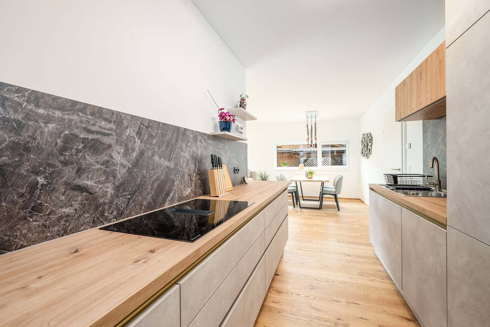 Una cocina moderna con tope de cocina negro, encimera de madera y armarios grises.