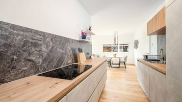 Una cocina moderna con tope de cocina negro, encimera de madera y armarios grises.