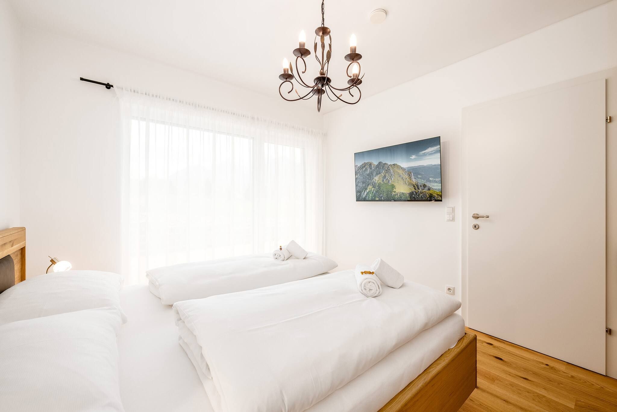 Una habitación de hotel con dos camas, un candelabro, un cuadro y una puerta.