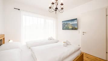 Una habitación de hotel con dos camas, un candelabro, un cuadro y una puerta.