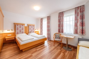 Habitación de hotel con una cama de madera, un escritorio y una silla.