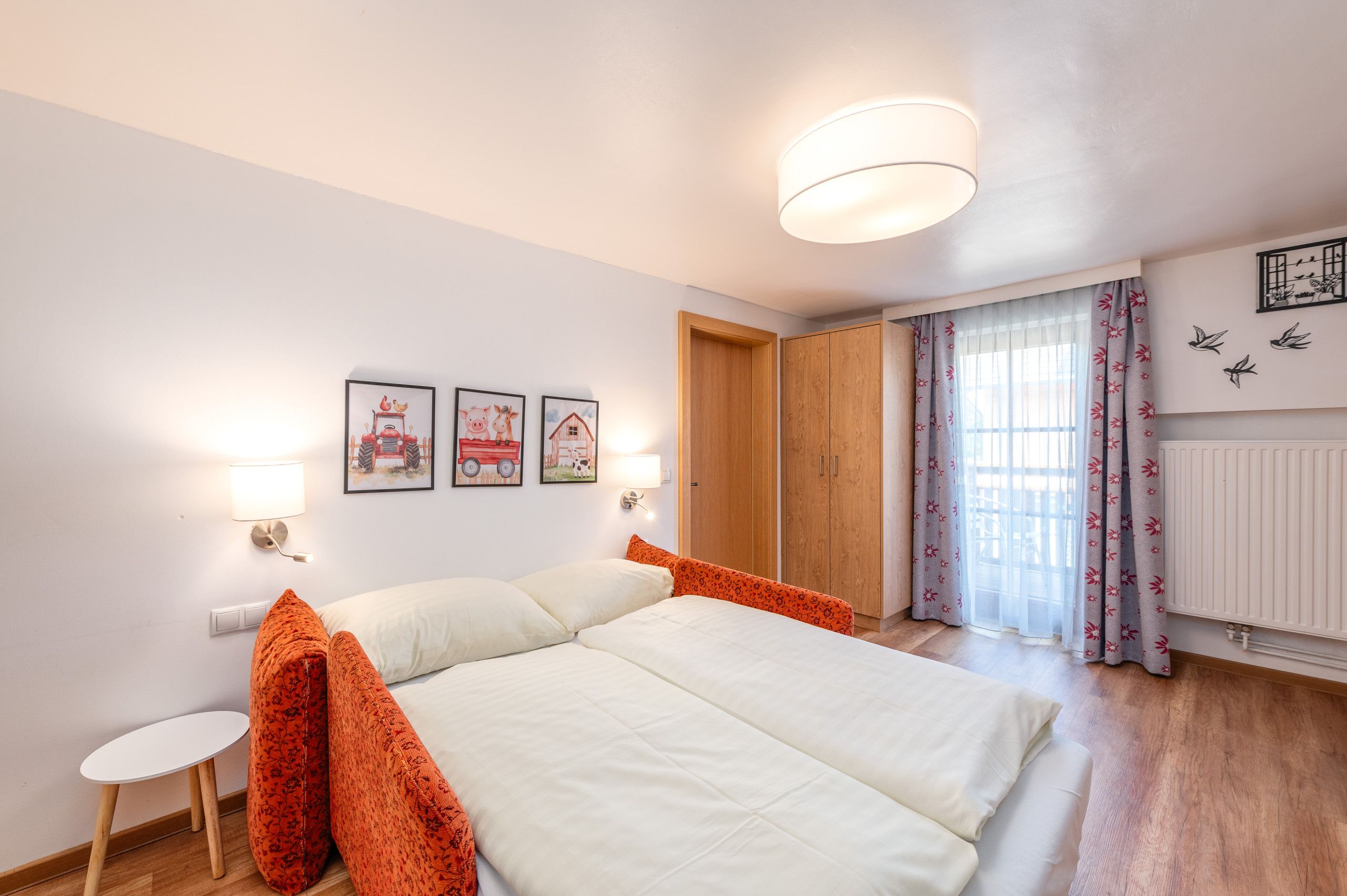 Ein Schlafzimmer mit einem Bett, zwei Wandlampen, einem Fenster mit Vorhängen und einer Heizung.