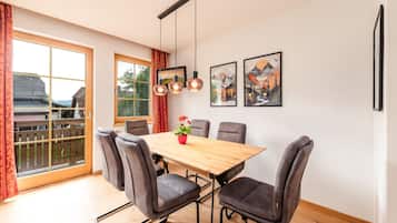 Un comedor con una mesa de madera y seis sillas, una planta en maceta y dos cuadros en la pared.