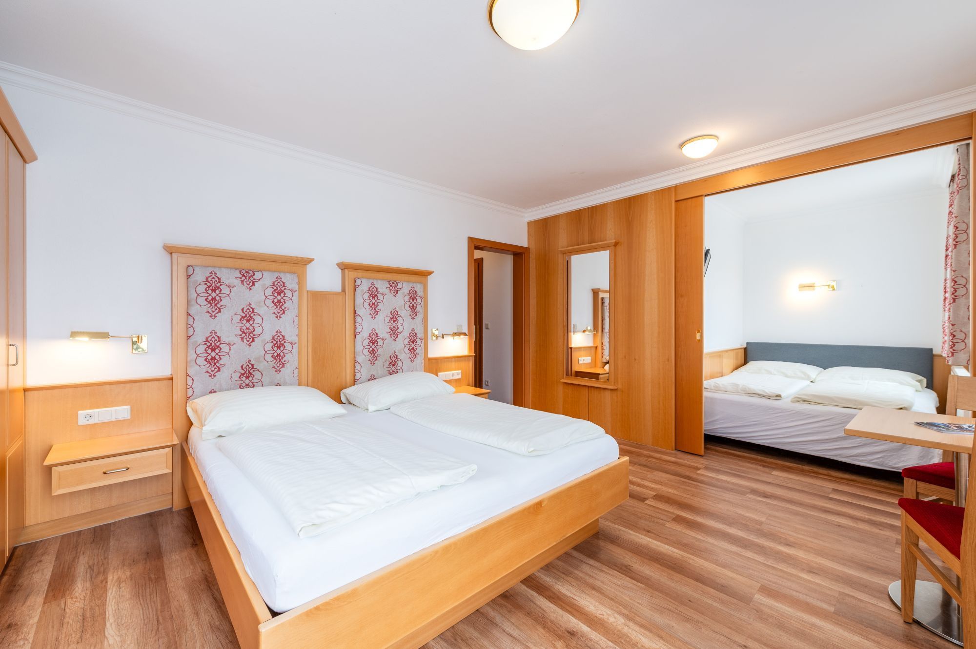 Una camera d'albergo con un letto grande, comodini, una scrivania e uno specchio.