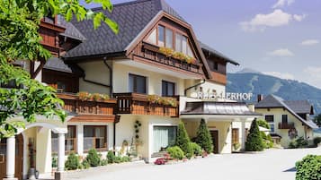 Un hotel de estilo alpino tradicional, con una entrada destacada que incluye un porche cubierto y jardineras en los balcones.