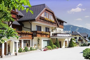 Un hotel de estilo alpino tradicional, con una entrada destacada que incluye un porche cubierto y jardineras en los balcones.