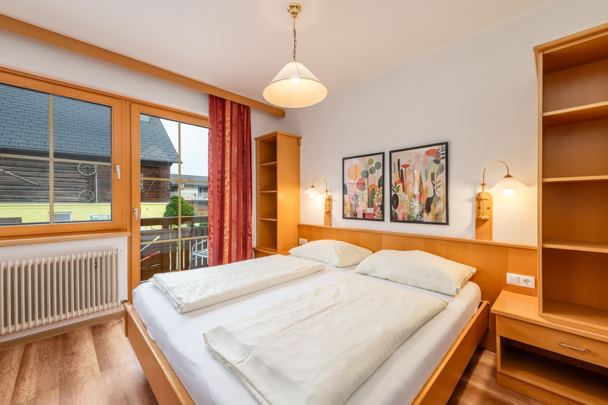 Habitación de hotel con una cama grande, una ventana con cortinas, un radiador y una obra de arte en la pared.