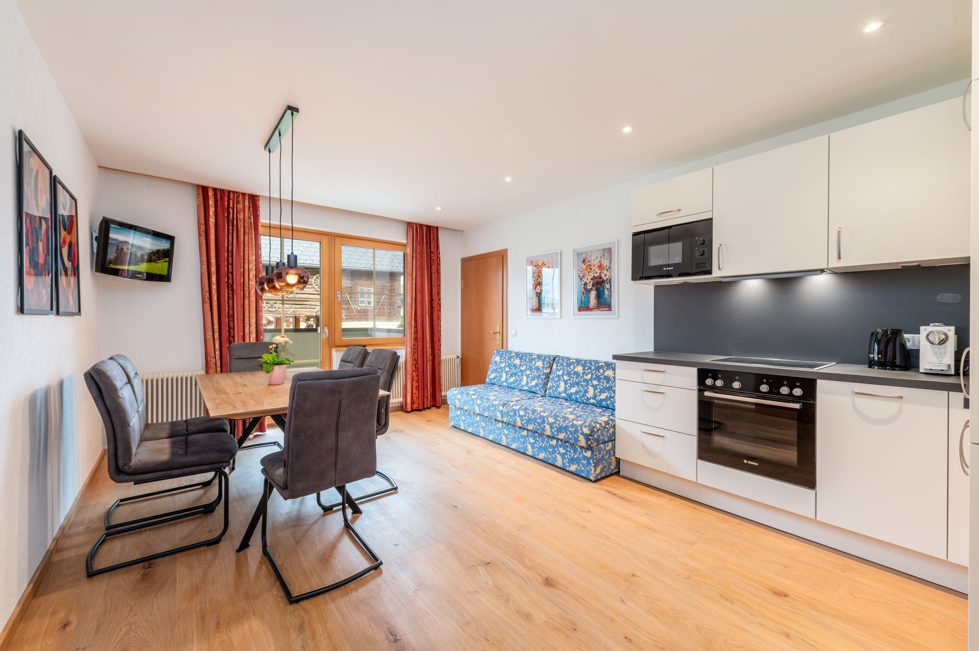 Una cocina moderna con armarios blancos, un horno Bosch y un comedor con mesa y sillas.