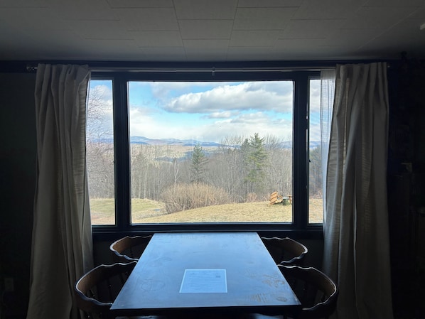 Une pièce avec une grande fenêtre, une table et deux chaises.