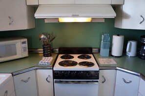 Une cuisine avec un four blanc, un four à micro-ondes et un mur vert.