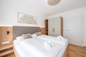 Ein modernes Schlafzimmer mit einem großen Bett, einem Holz-Kopfteil, einem Nachttisch, einem Kleiderschrank und einer Wandleuchte.