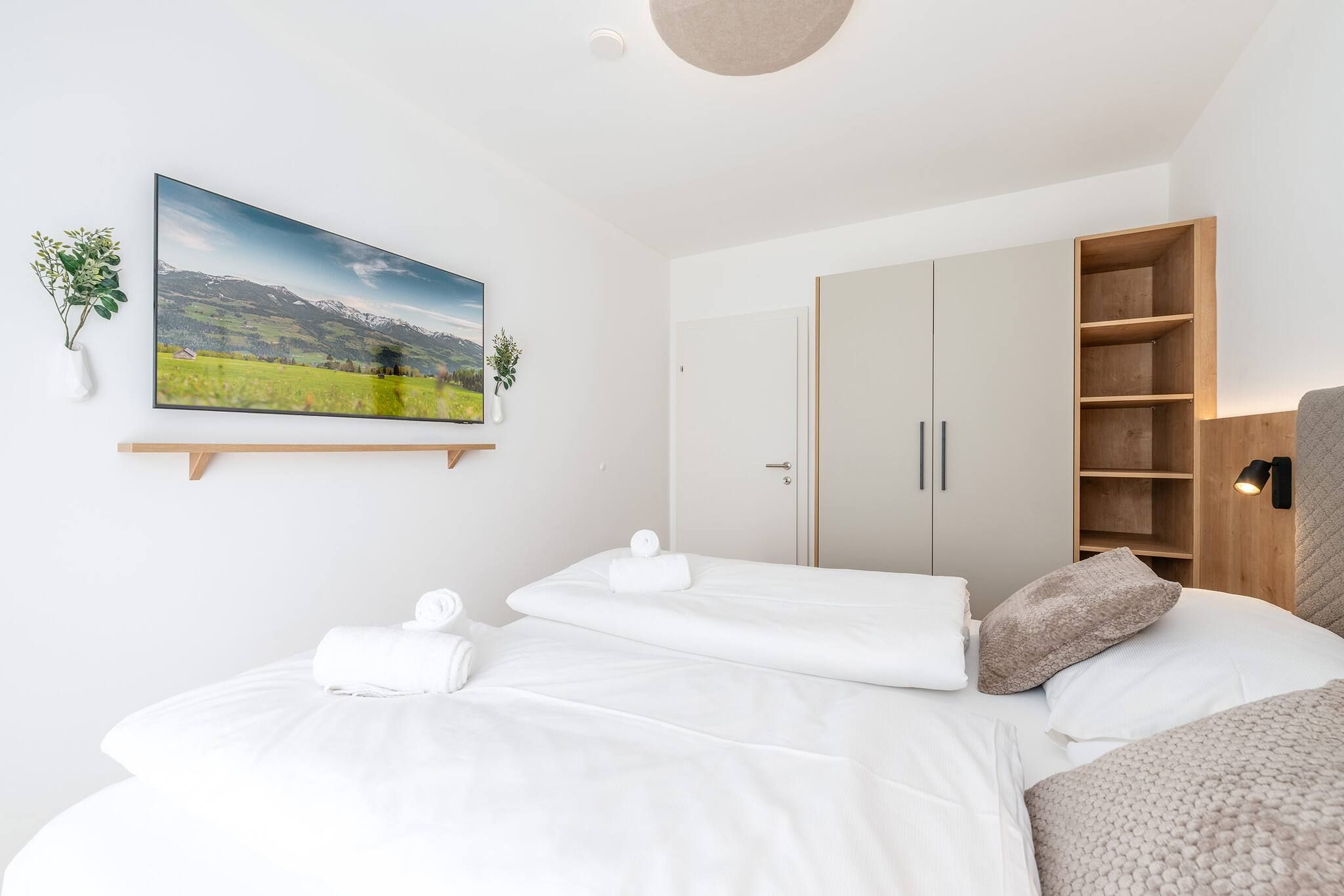 Une chambre à coucher avec un lit, une armoire, une table de chevet avec une lampe et un tableau accroché au mur.