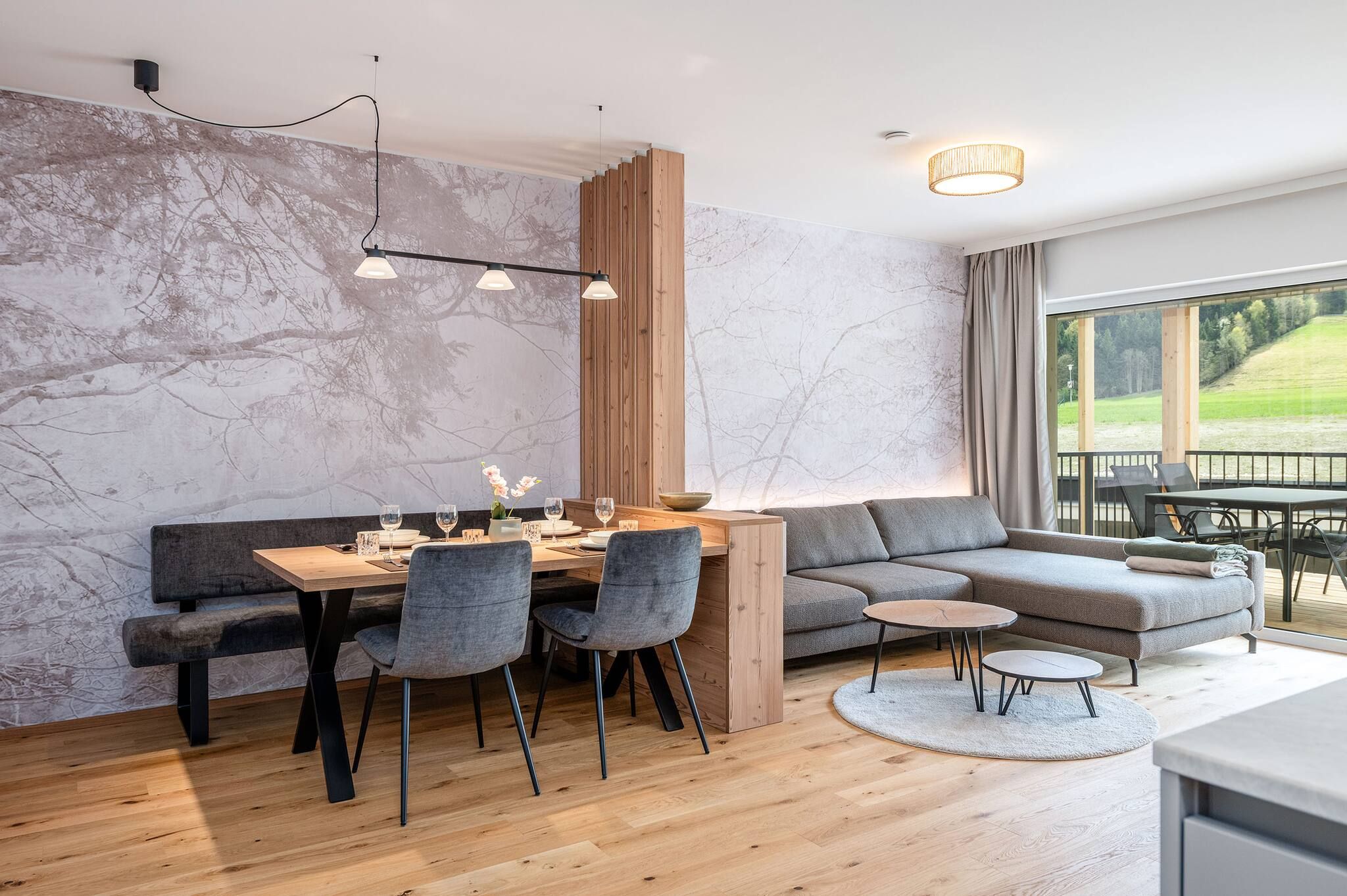 Ein modernes Wohnzimmer mit Essbereich, einer Couch, einem Couchtisch und Blick ins Freie.