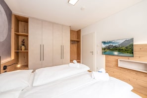 Ein Hotelzimmer mit Bett, Kleiderschrank, Fernseher und einem Gemälde.