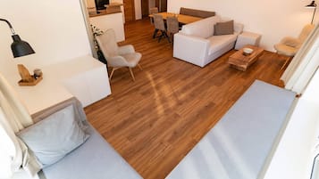 Ein modernes Wohnzimmer mit einer Couch, einem Esstisch und einer Küche im Hintergrund.