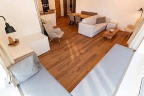 Ein modernes Wohnzimmer mit einer Couch, einem Esstisch und einer Küche im Hintergrund.