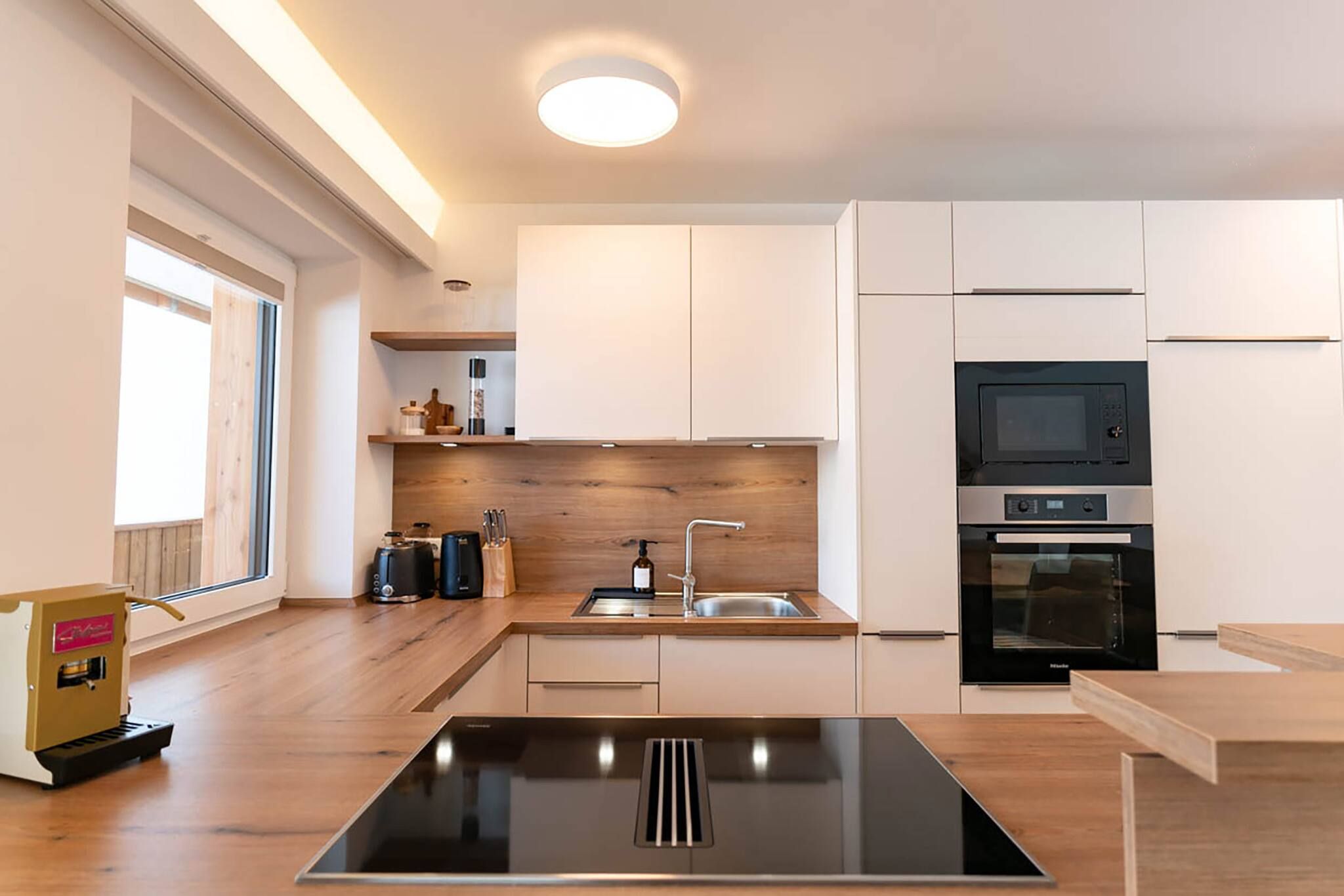A modern kitchen with a central island, built-in appliances, and a window for natural light.