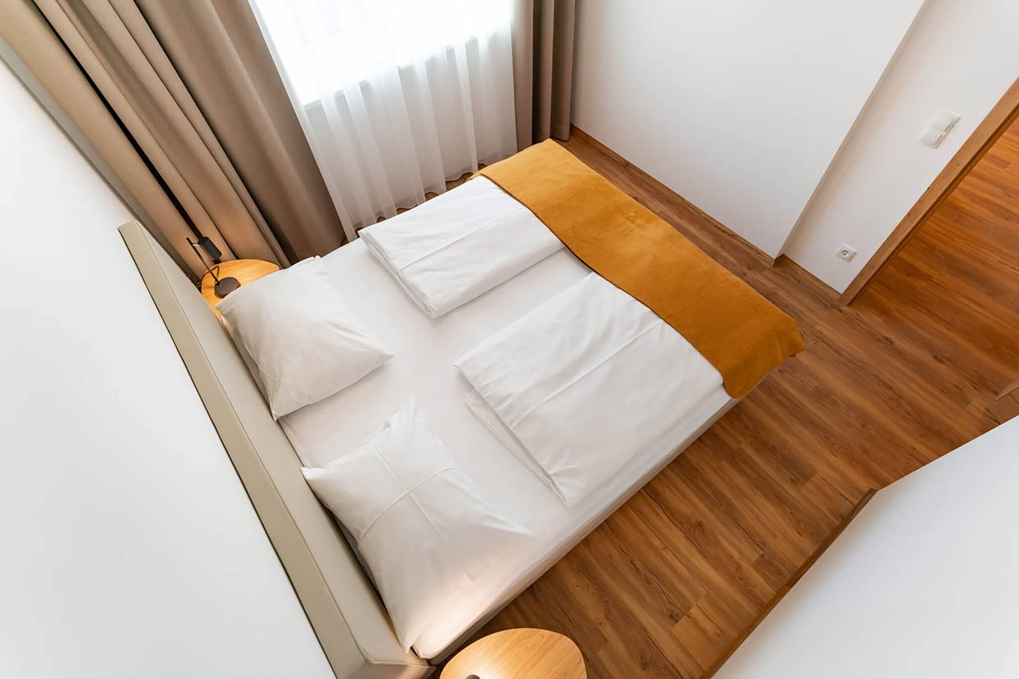 A bedroom with a bed, a bedside table, and a window with curtains.