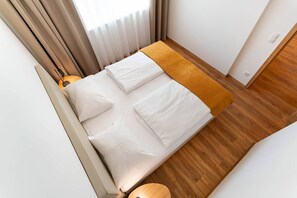 A bedroom with a bed, a bedside table, and a window with curtains. - Waldrand Apartments - Amsel 5 (Ramsau)