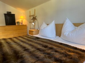 Ein Hotelzimmer mit einem Bett, weißen Kissen, einem hölzernen Kopfteil, einem Nachttisch mit Lampe und einer Sterndekoration.