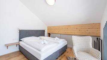 Ein Schlafzimmer mit einem Bett, einem Sessel, einem hölzernen Kopfteil und einer Lampe.