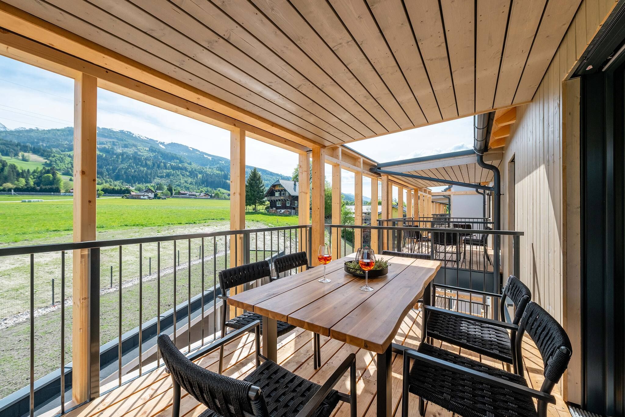 Eine Holzterrasse mit Tisch und Stühlen, mit Blick auf eine grüne Landschaft.