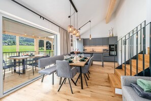 Ein modernes Interieur mit Essbereich, Küche und einem Balkon mit Blick auf die Landschaft.
