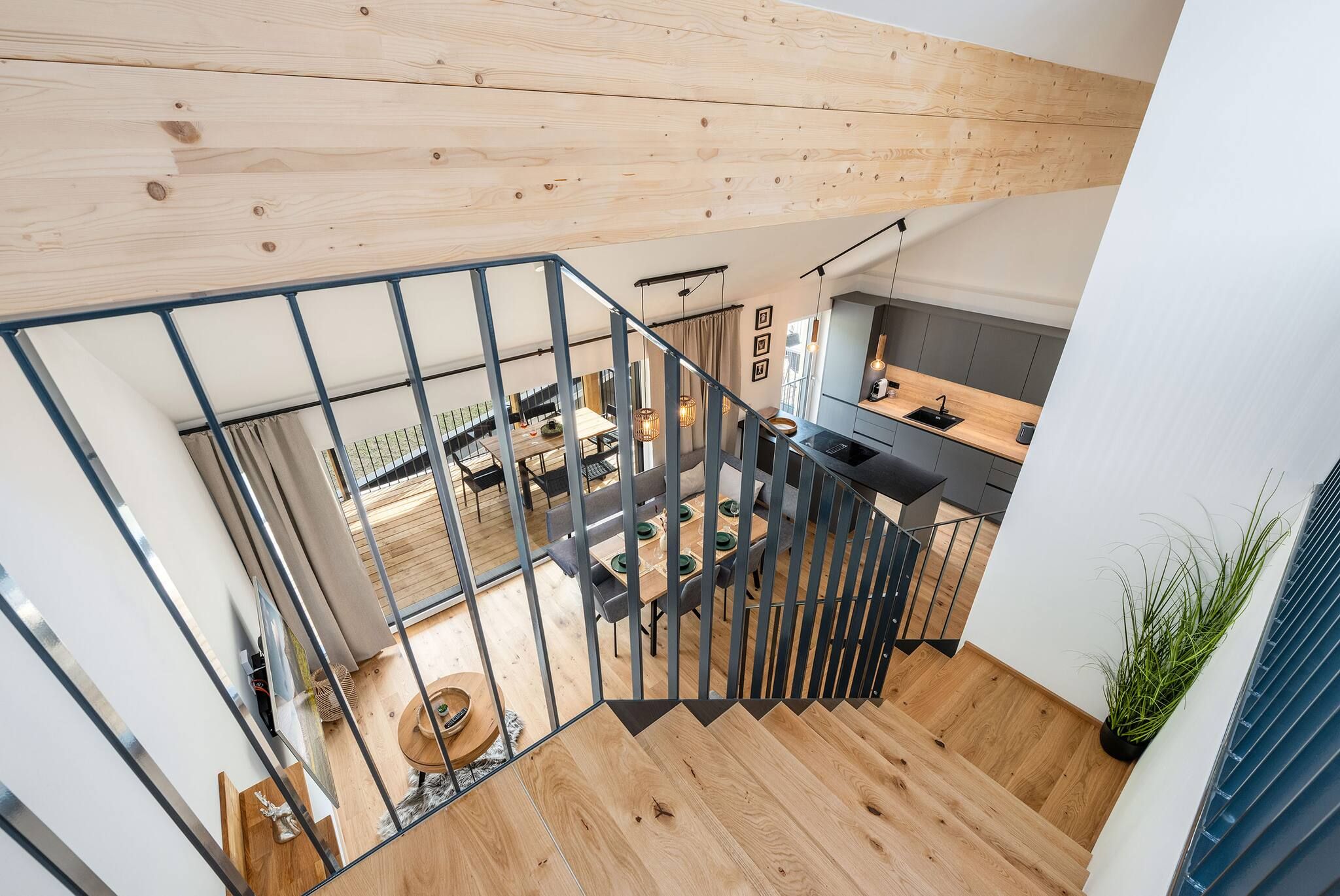 Un intérieur moderne avec un escalier, un plancher en bois et un coin cuisine.